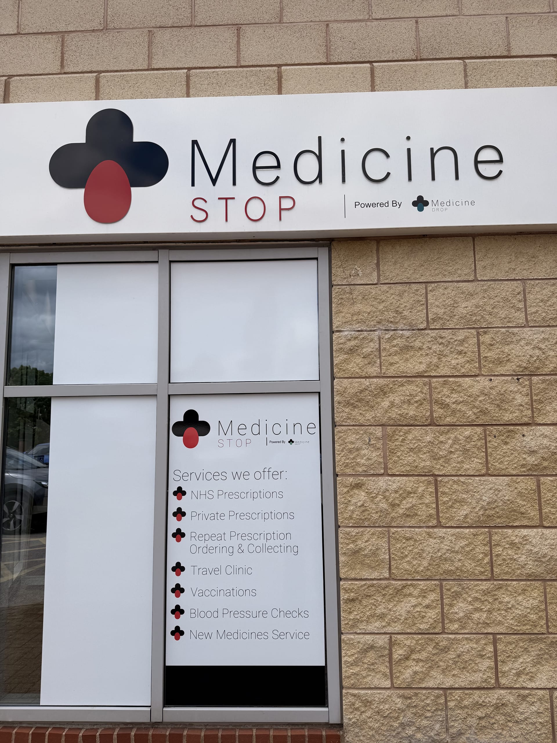 Medicine Stop signage with a list of services displayed in the window.